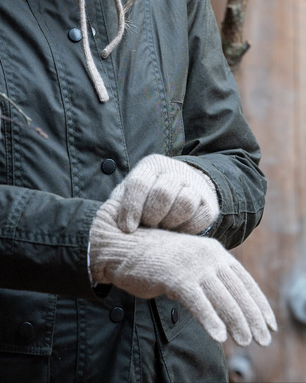 Person wearing a green jacket and beige gloves in a natural setting
