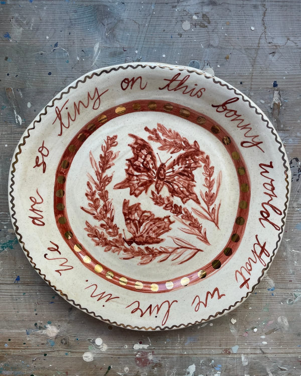 Decorative plate with butterfly design and text on a textured surface