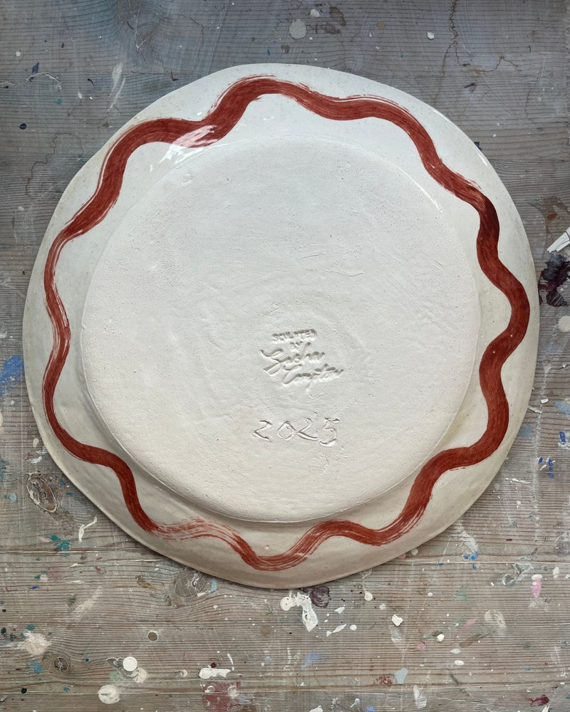Ceramic plate with red decorative edge on a gray surface