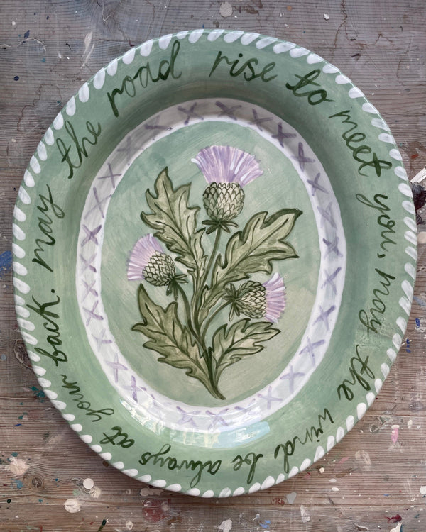 Decorative plate with floral design and text on a wooden surface