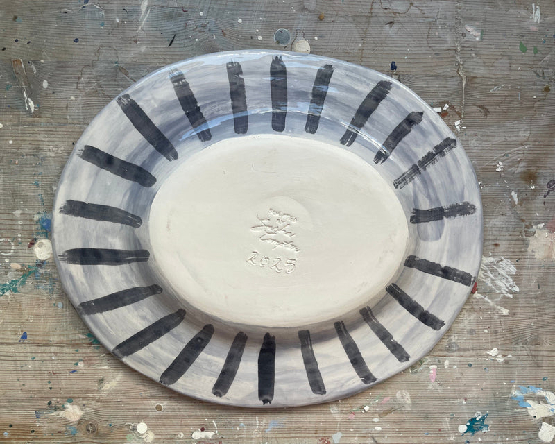 Ceramic plate with black stripes on a textured surface