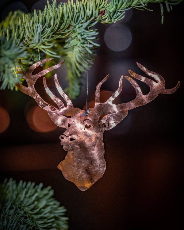 Decorative deer head ornament on a branch with a blurred bokeh background