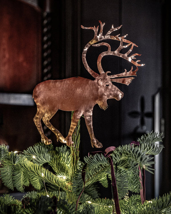 Decorative copper reindeer on a Christmas tree with a dark background