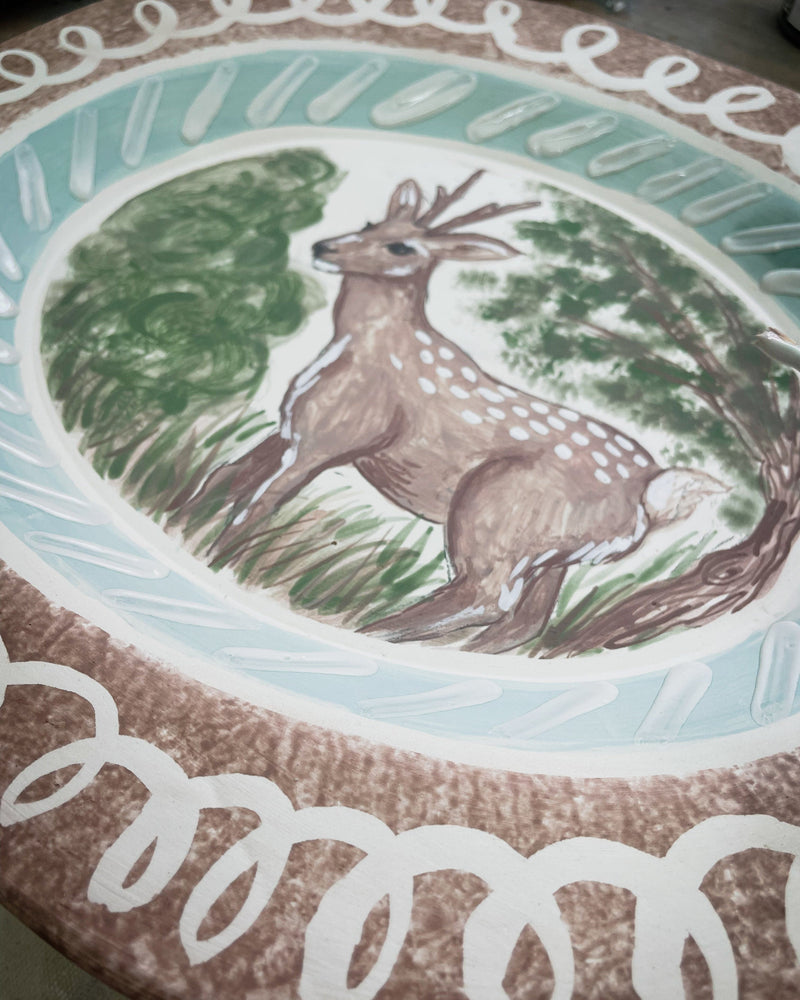 Decorative plate with a deer illustration in a natural setting