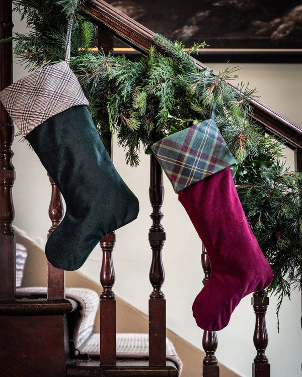 Christmas stockings hanging on a staircase with greenery