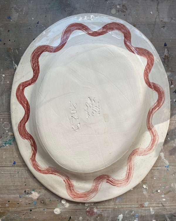 White ceramic plate with red decorative border on a gray surface
