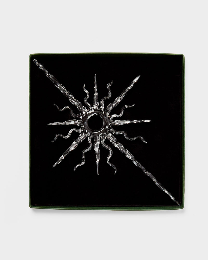 Black square box with a glass sun-like decoration on a white background